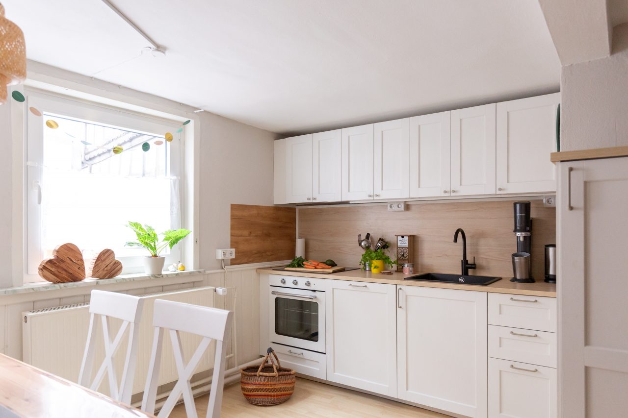 Helle, modern ausgestattete Küche mit Backofen, Spüle, Kaffeemaschine und Essplatz am Fenster