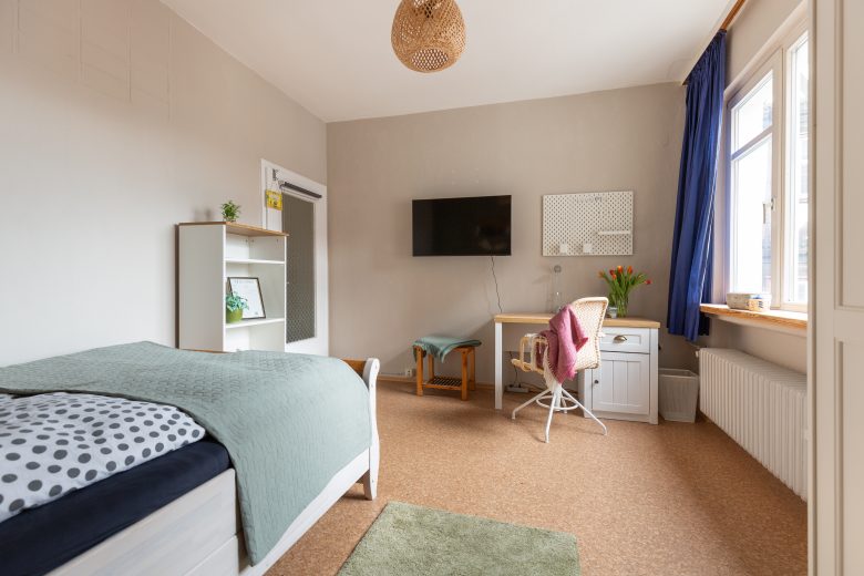 Helles Gästezimmer zur Vermietung mit Bett, Schreibtisch am Fenster.  Wie alle Gästezimmer mit einen großen Fernseher.