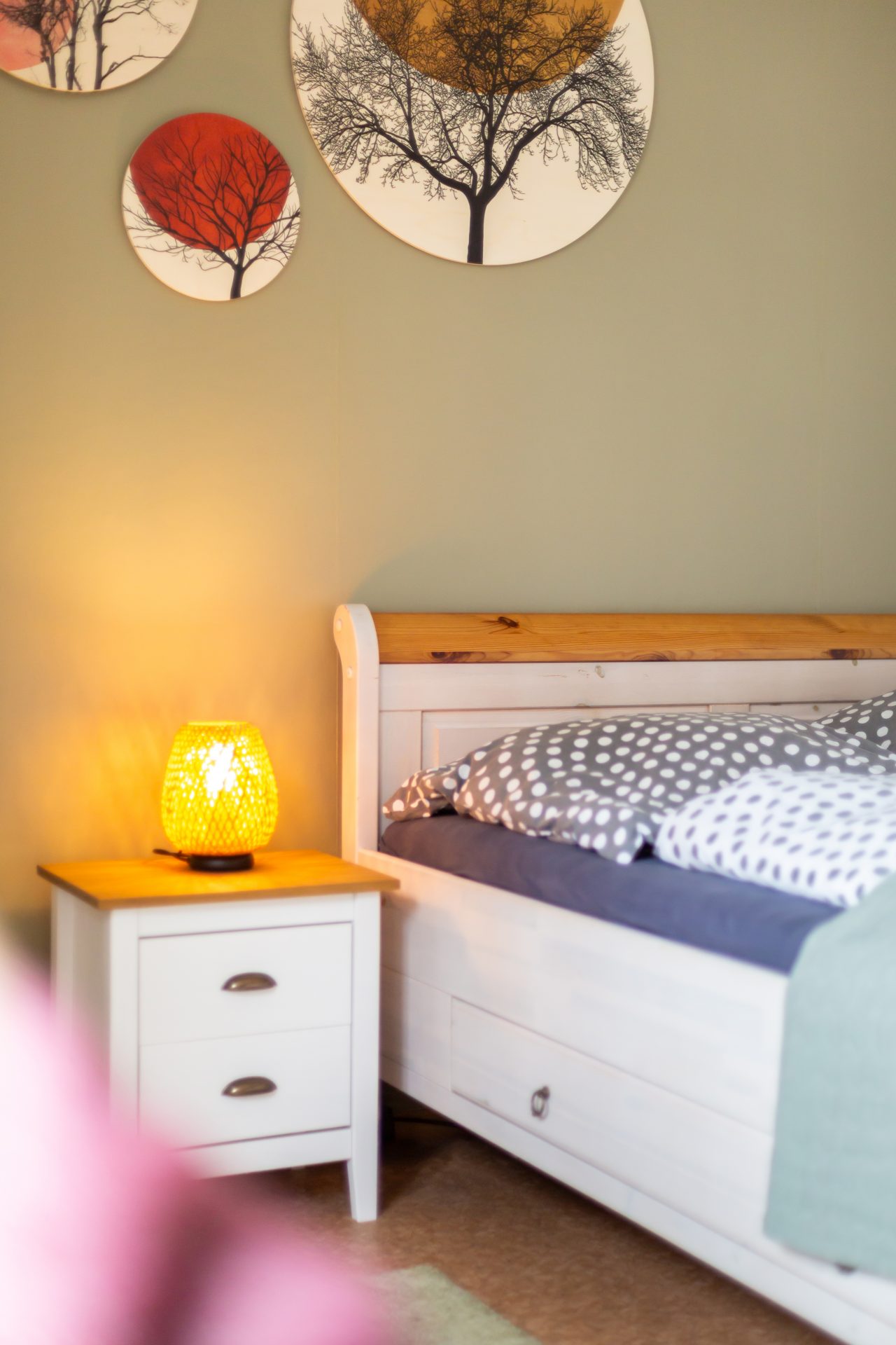 Gemütliches Einzelbett im Gästezimmer mit Nachttisch, warmer Lampe und dekorativen Wandbildern
