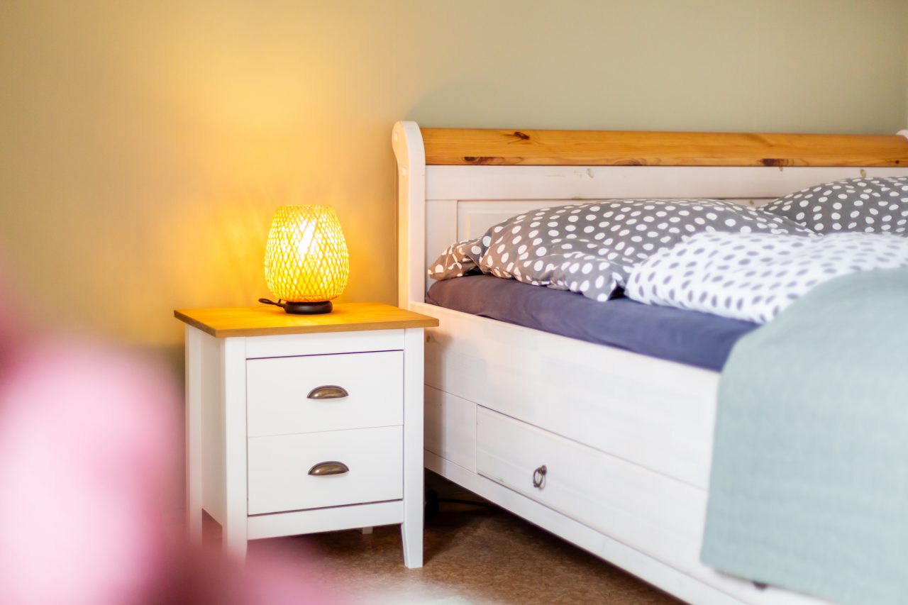 Gemütliches Einzelbett im Gästezimmer mit Nachttisch, warmer Lampe und dekorativen Wandbildern